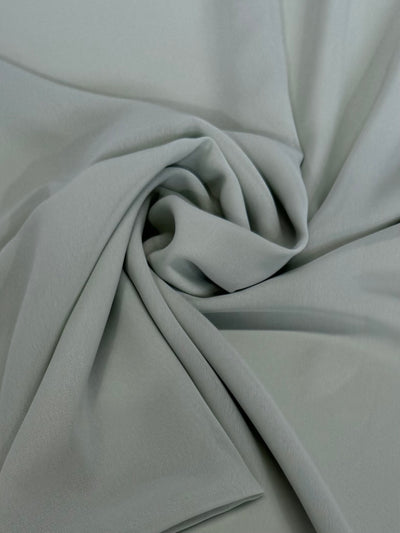 Hi-Multi Chiffon - Sea Foam by Super Cheap Fabrics is a light gray, lightweight fabric with a soft texture. It features elegant folds and curves in a swirling, twisted pattern at the center. Width: 148cm.