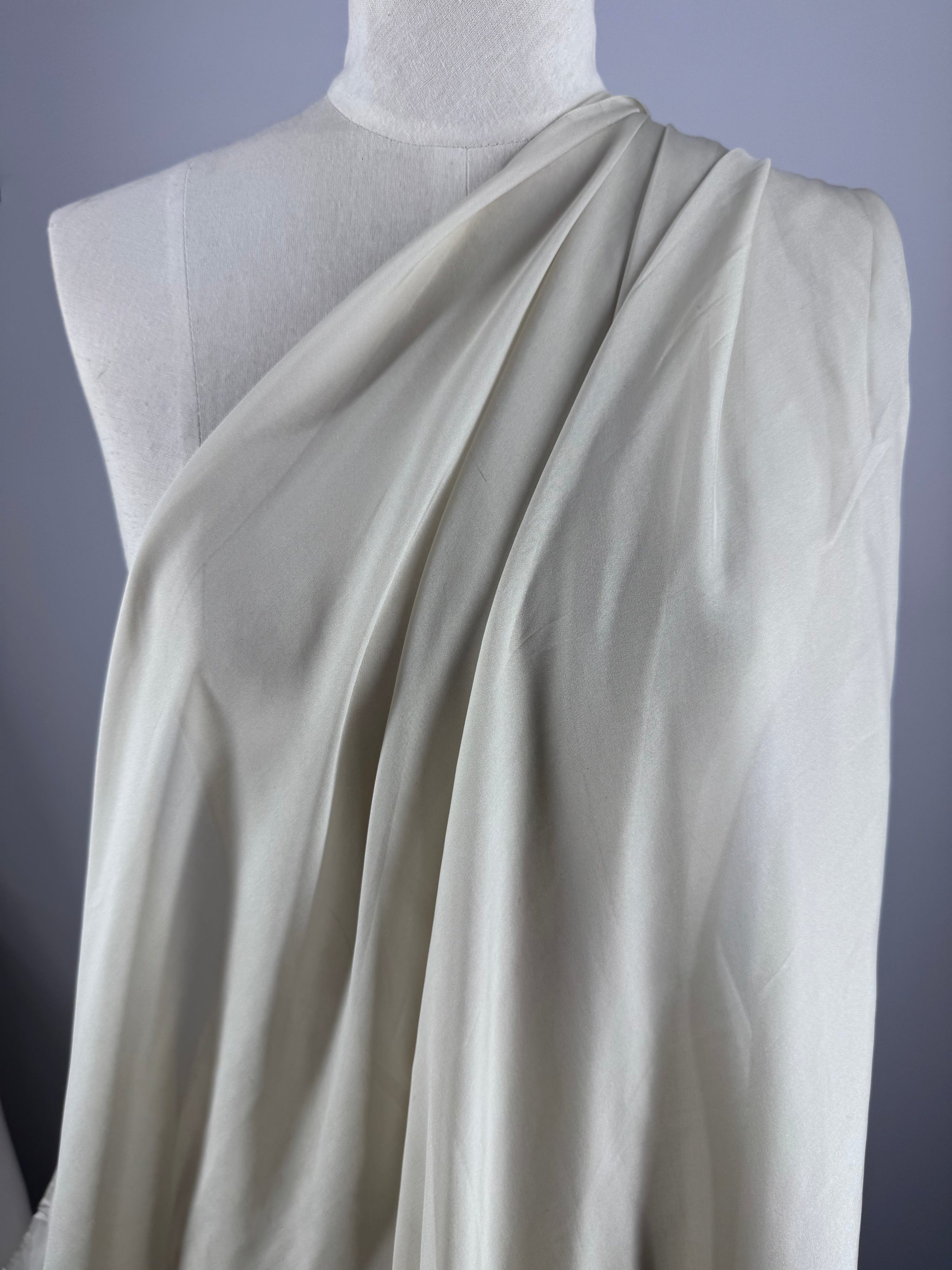 Super Cheap Fabrics’ Pure Silk Chiffon - Oyster (140cm) is draped elegantly on a white dress form, showcasing its lightweight, soft folds—perfect for summer outfits—against a light gray background.
