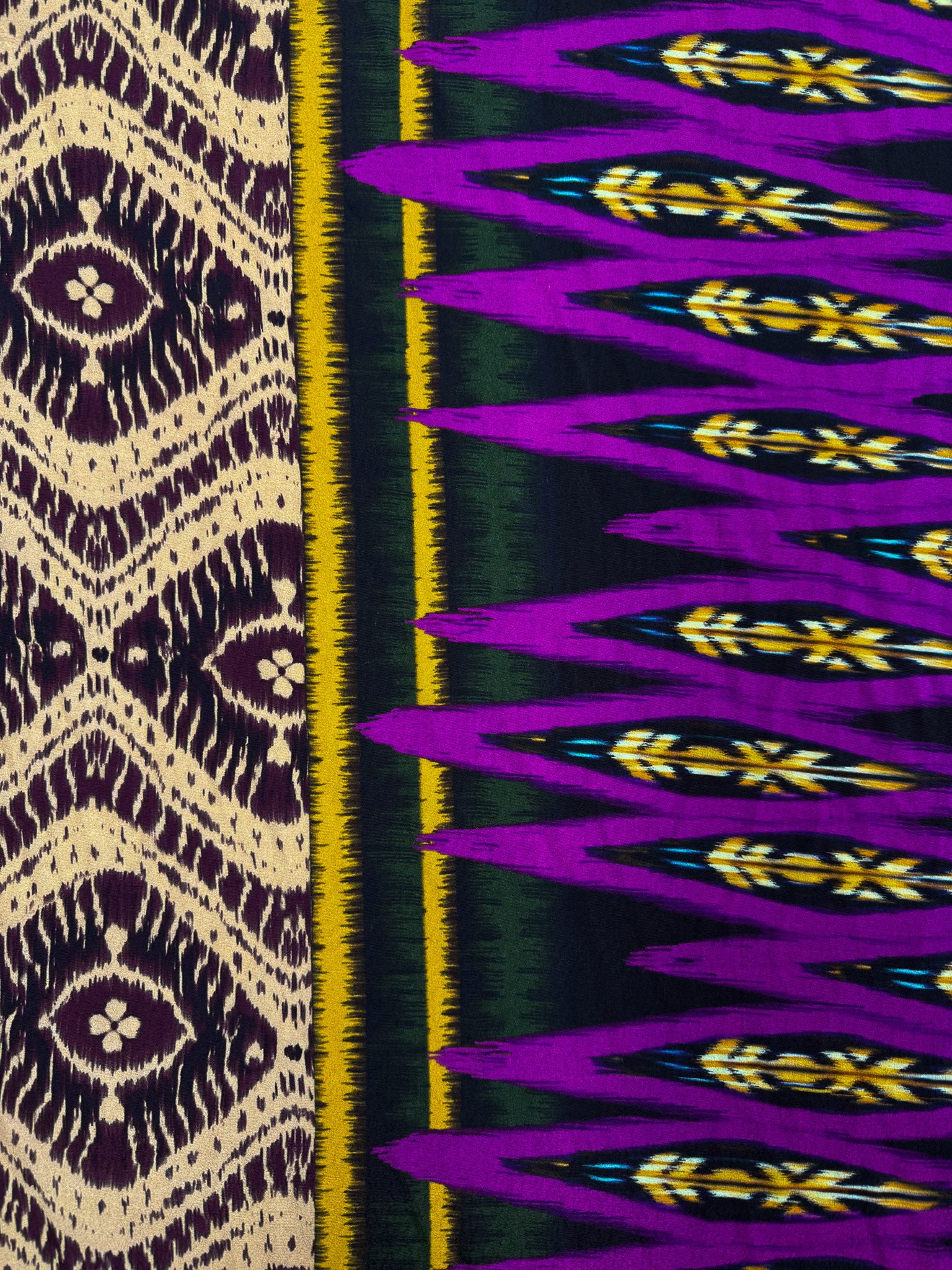 Super Cheap Fabrics’ Printed Viscose - Regal Ikat (145cm) features two striking patterns: cream and dark purple diamonds on one side, and bold purple, yellow, green, and black geometric jagged lines on the other.