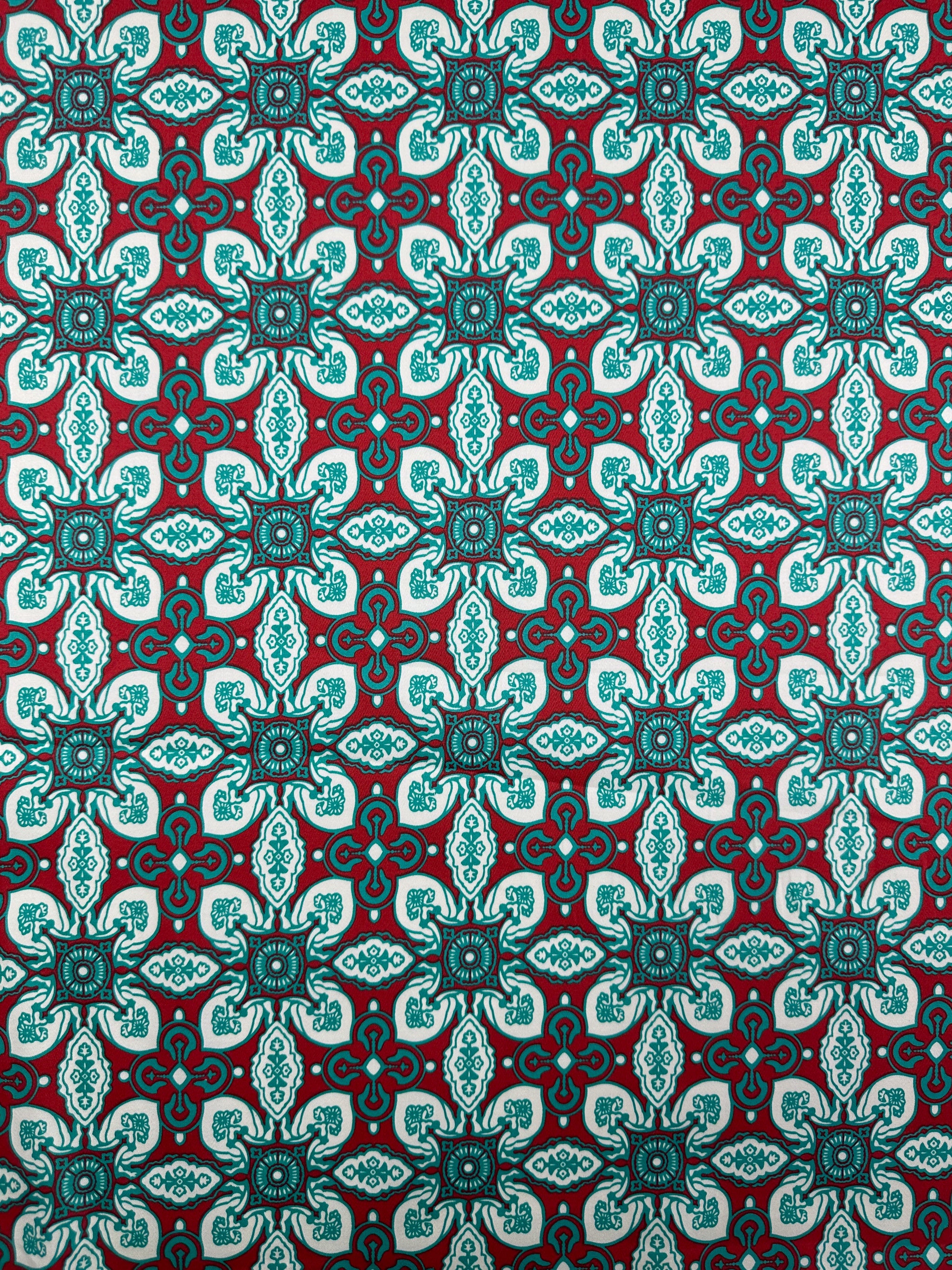The Cotton Sateen - Mural - 150cm from Super Cheap Fabrics features a teal and white geometric cross motif on dark red, perfect for adding a vibrant decorative touch to your home décor.