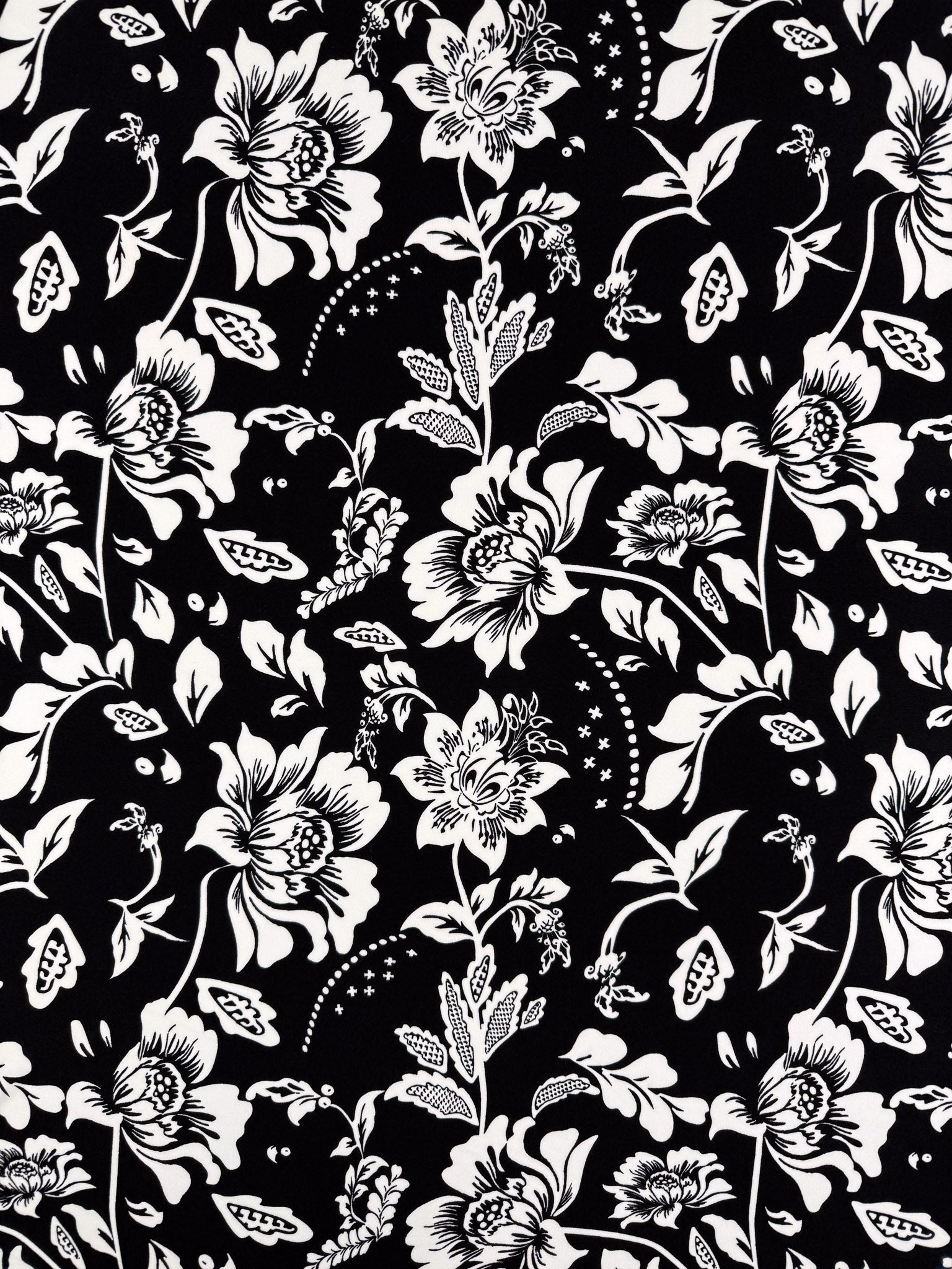 Super Cheap Fabrics’ Printed Lycra - Monochrome Botanica - 150cm features a black and white floral print with large flowers and buds on medium weight lycra, offering comfort and versatility in a symmetrical repeating design.