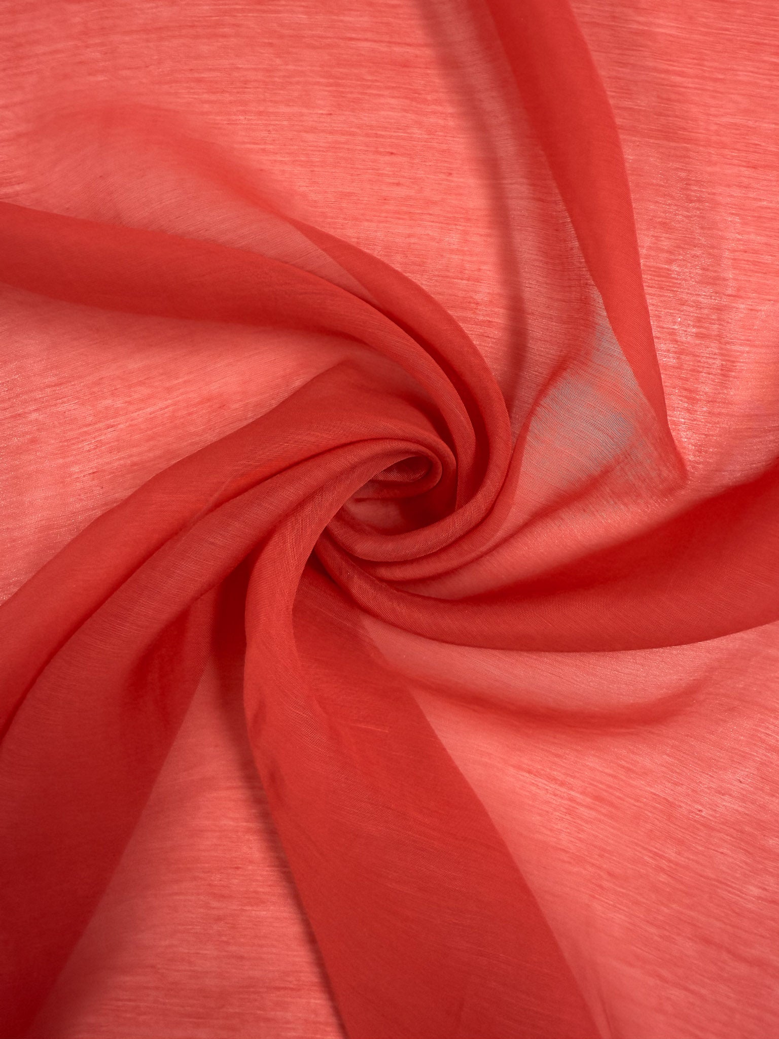 Designer Voile - Paprika - 150cm from Super Cheap Fabrics features sheer red fabric with a swirling spiral pattern, making it ideal for airy summer dresses with soft folds and subtle shade variations.