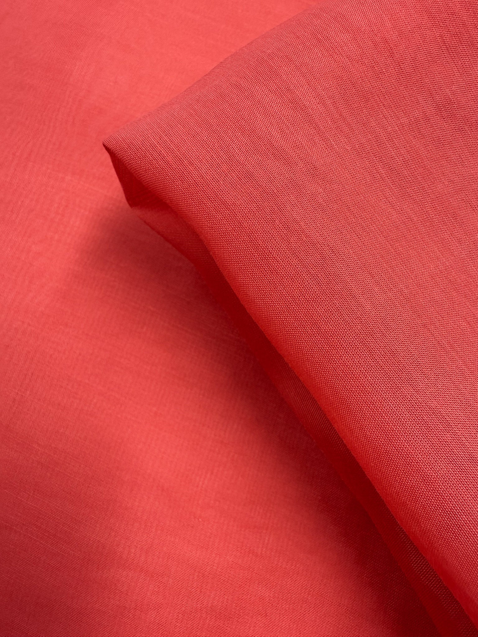 A close-up of Super Cheap Fabrics' Designer Voile - Paprika (150cm) shows its soft, slightly sheer texture and smooth, lightweight look, neatly folded—ideal for summer dresses.