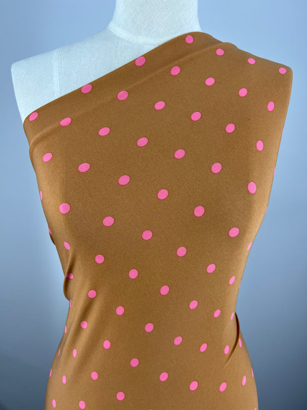 A dress form displays Super Cheap Fabrics' Printed Lycra - Pecan & Pink Polka - 150cm, a brown polyester spandex with a one-shoulder style and evenly spaced pink polka dots.